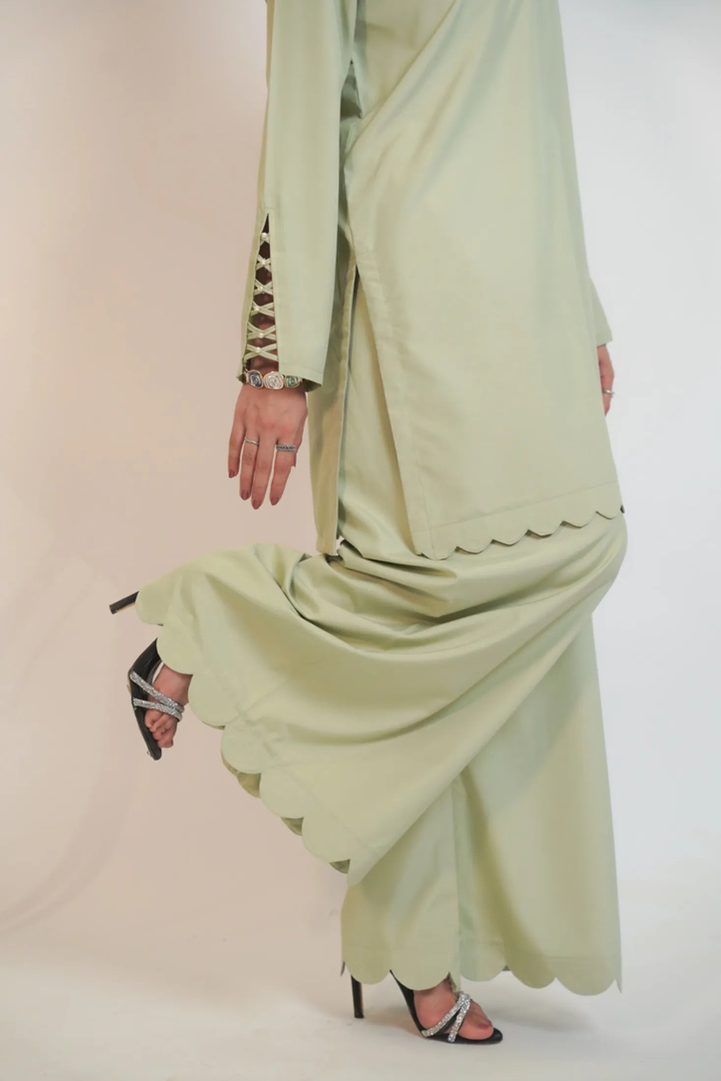 Person wearing a light green dress with a plain background