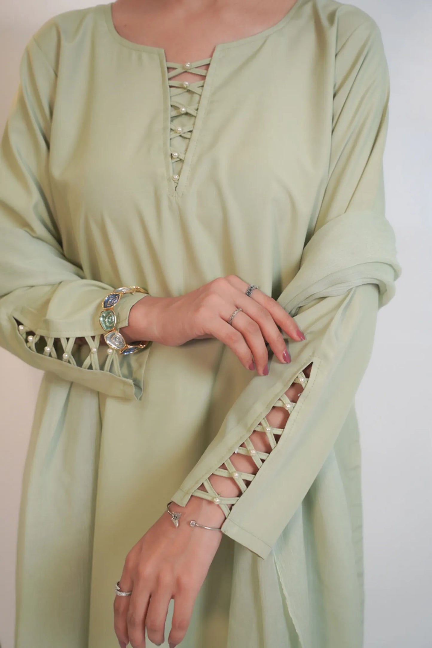 Light green dress with lace-up details on a plain background