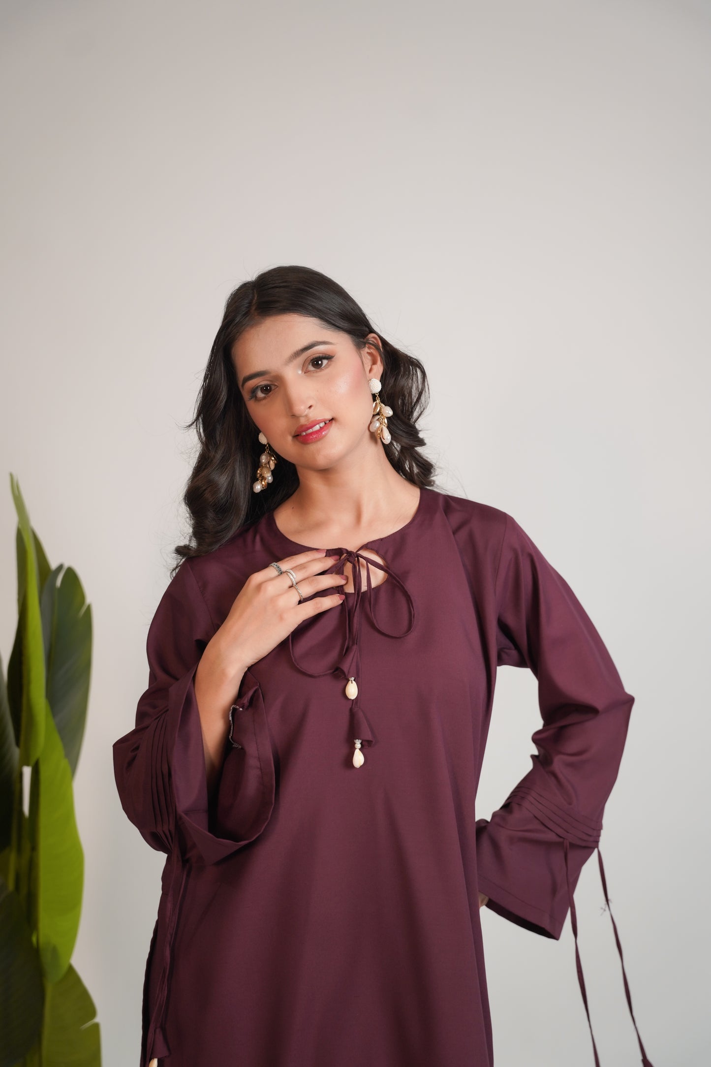 Woman wearing a burgundy long-sleeve top with a white background