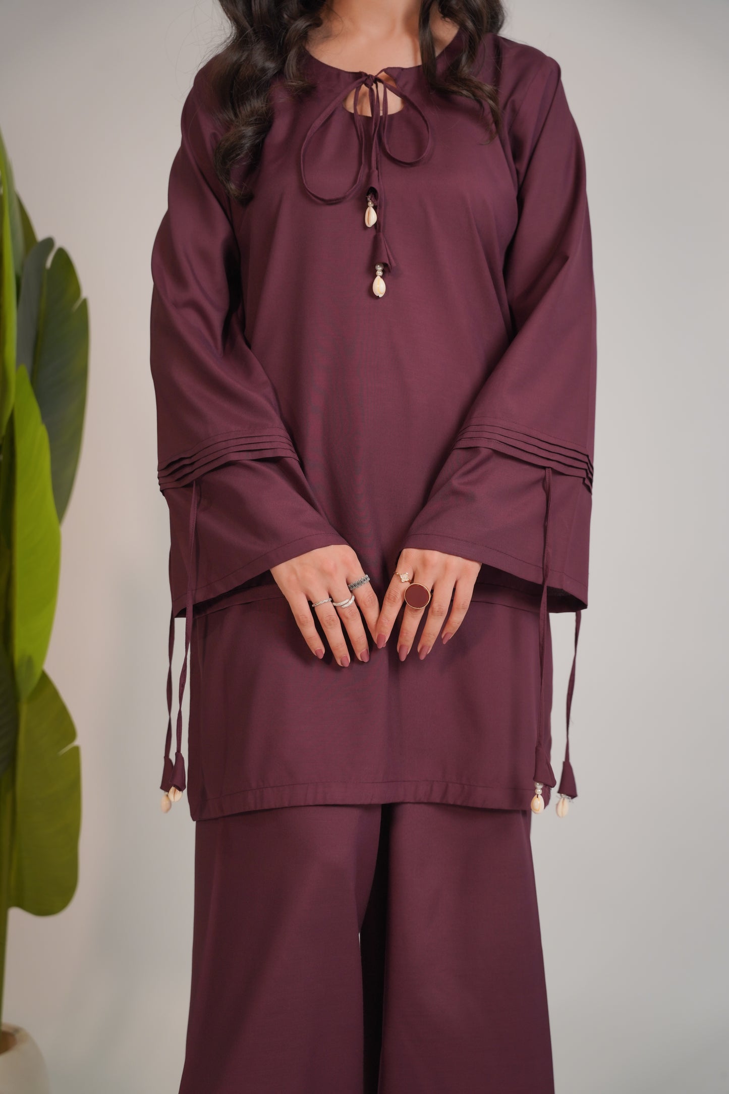 Maroon outfit with long sleeves and wide-leg pants on a neutral background