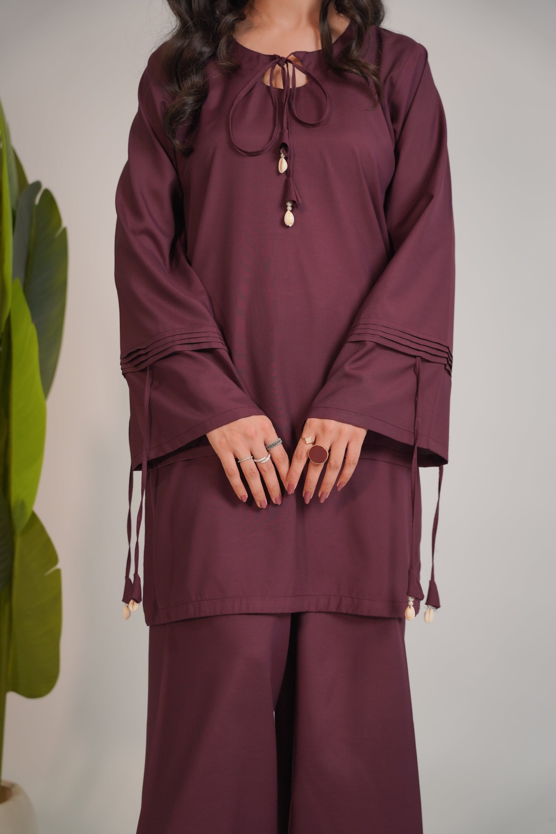 Maroon outfit with long sleeves and wide-leg pants on a neutral background