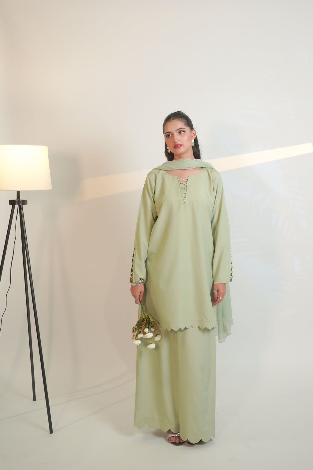 Woman wearing a light green traditional outfit with a white background