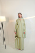 Woman wearing a light green traditional outfit with a white background