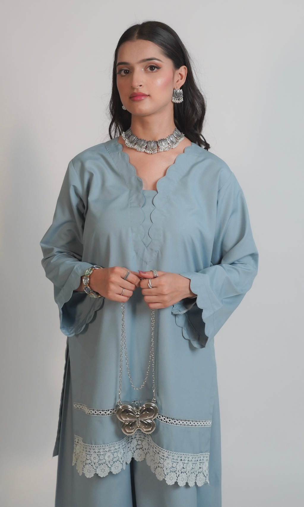Woman wearing a light blue kurta with lace details on a plain background