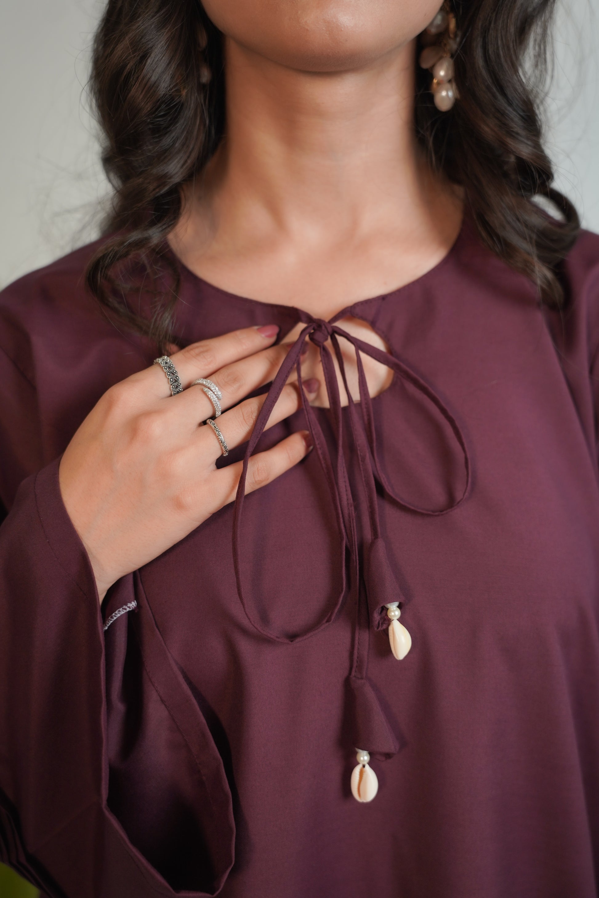 Close-up of a person wearing a burgundy top with decorative elements.